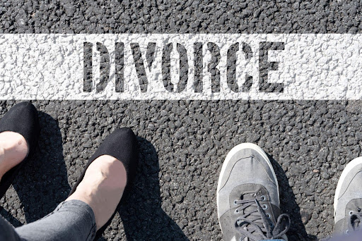 Two spouses stand in front of the word divorce written on the road